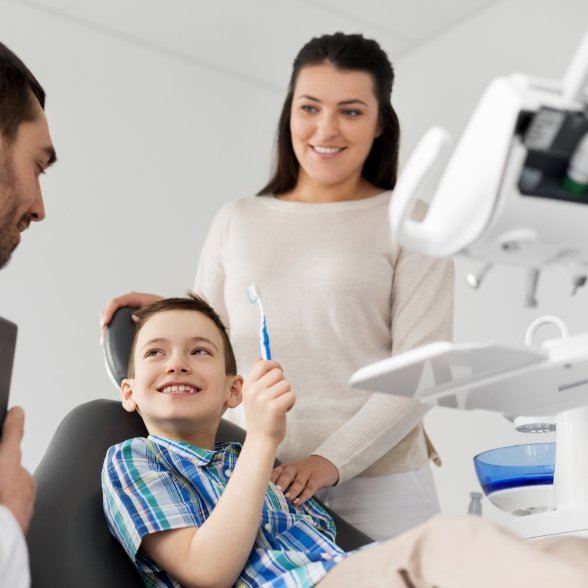 Mother and son in dental treatment room talking to dentist