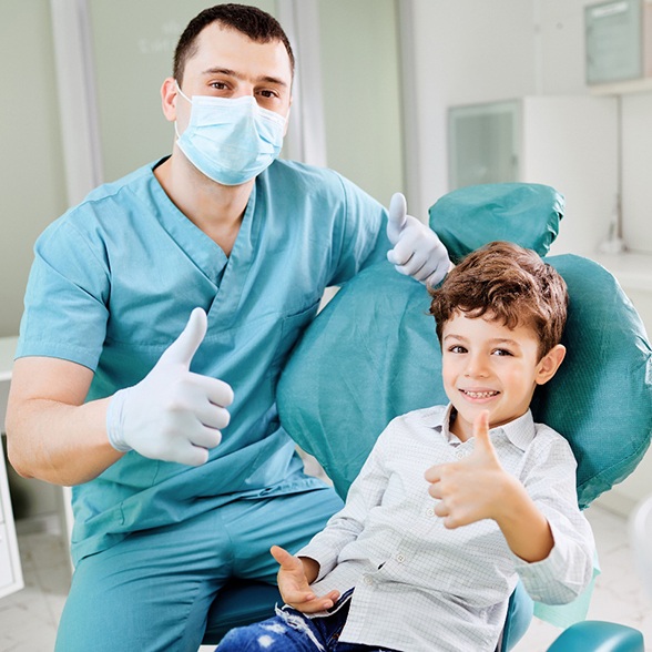 A happy dentist and young boy giving thumbs up