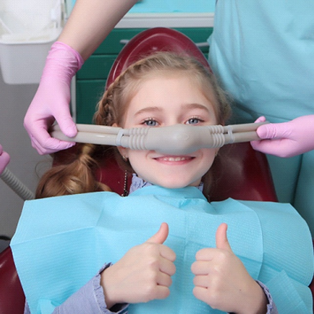 A little girl having a nasal mask placed over her nose before receiving nitrous oxide at a practice that offers sedation dentistry in Chesterfield