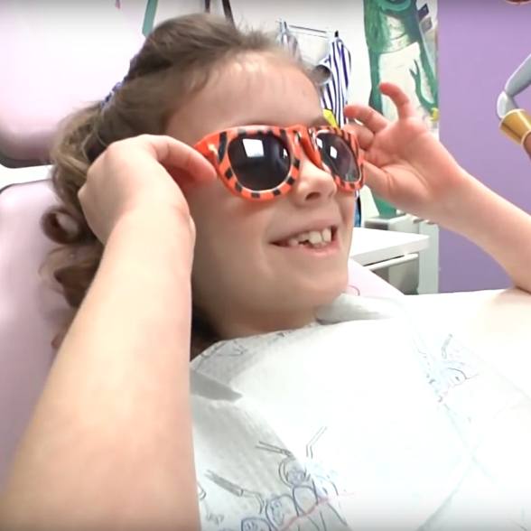 Smiling child putting on sunglasses in dental office