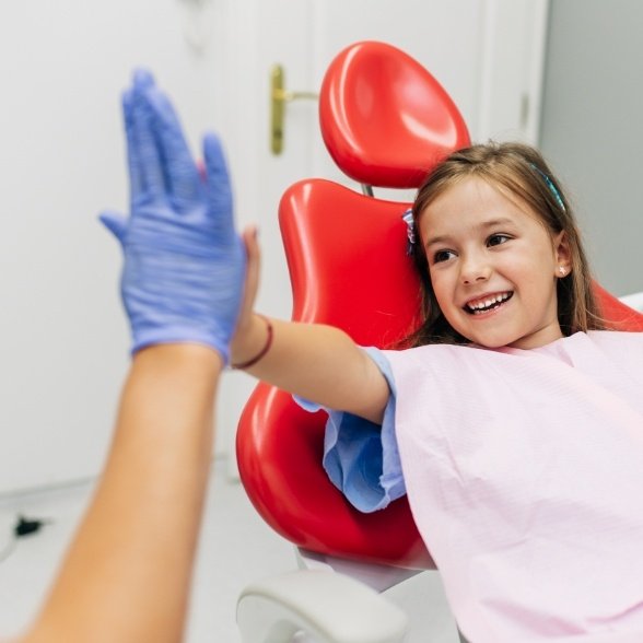 Smiling child giving her dentist a high five
