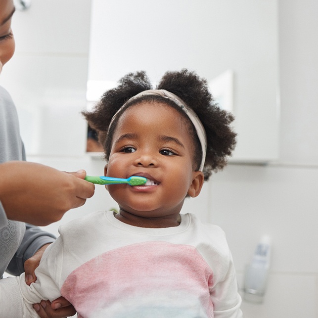 a mother brushing her daughter’s teeth