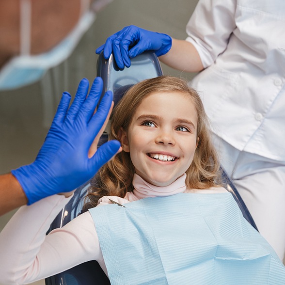 a child high-fiving their pediatric dentist