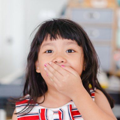 Child with broken tooth covering face