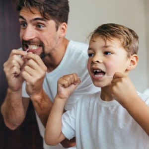 a father and son flossing their teeth together