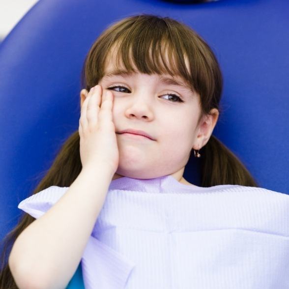 Young girl holding cheek in pain before tooth extraction
