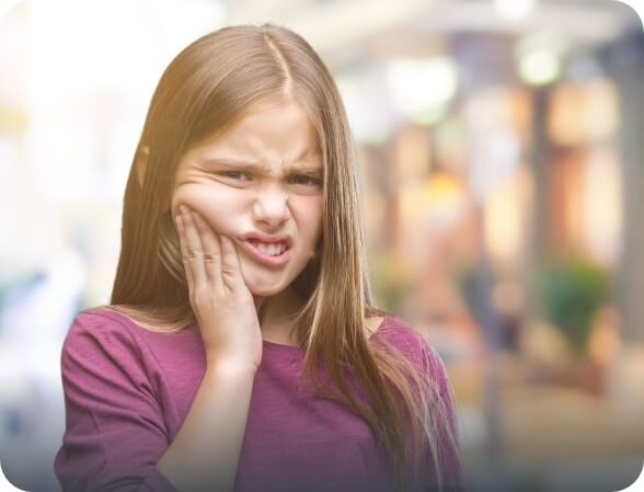 Young girl holding her cheek in pain