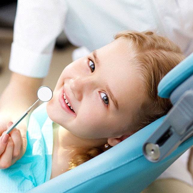 A young girl smiling as her dentist prepares to administer fluoride treatment in Chesterfield