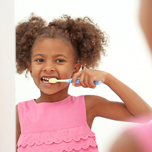 A little girl brushing her teeth while standing in front of the mirror in her bathroom in Chesterfield