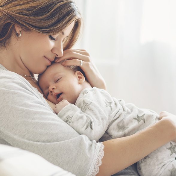 Mother holding baby while in bed