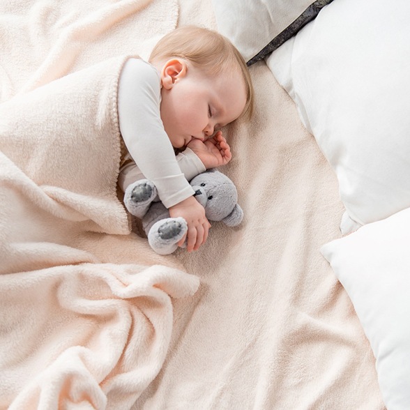 Baby sucking their thumb while sleeping with stuffed animal