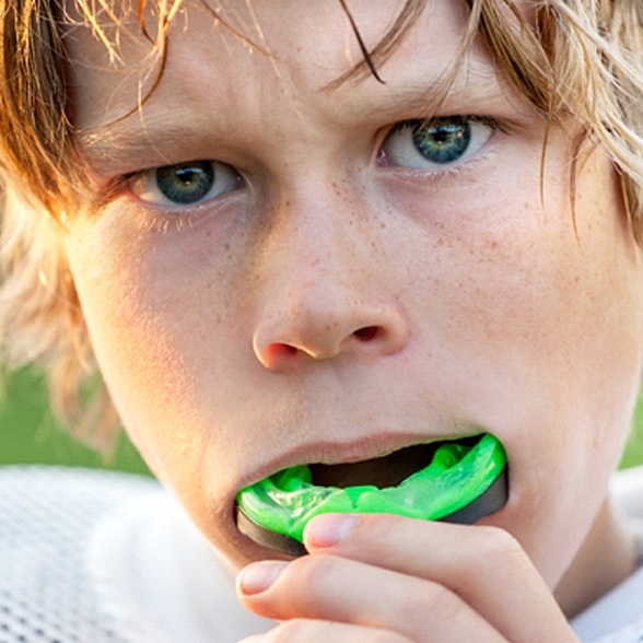 A young boy inserts an athletic mouthguard before playing football