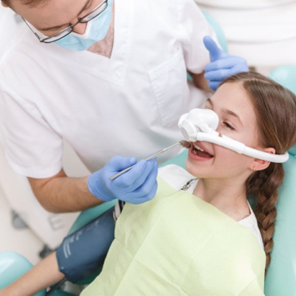 A young girl experiencing the effects of nitrous oxide while a dentist perform a regular dental exam