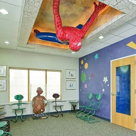 Pediatric dental office reception area with planets on walls spiderman in ceiling and E T statue