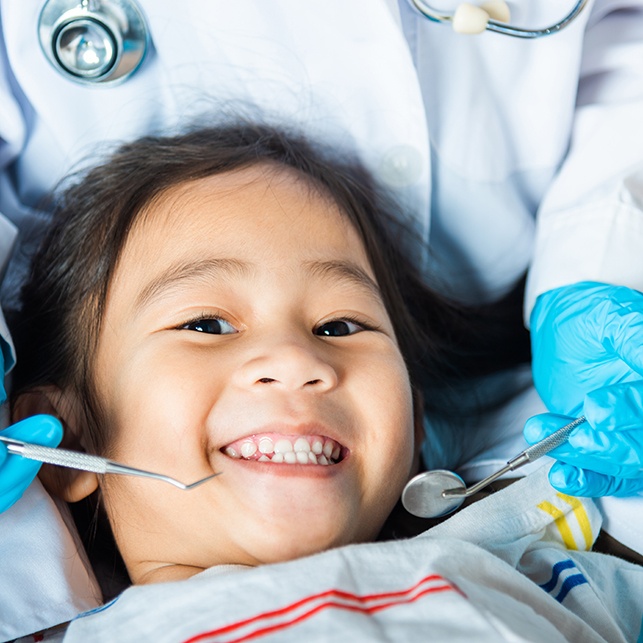 a child receiving an oral cancer screening from a pediatric dentist