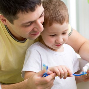 father and son cleaning teeth in bathroom