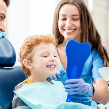 Young boy looking at smile after preventive dentistry