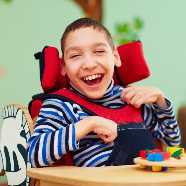 Laughing child in wheelchair after special needs dentistry visit