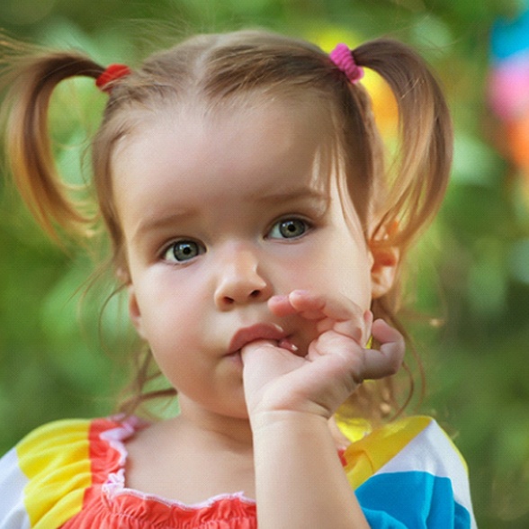 A little girl with pigtails sucks her thumb