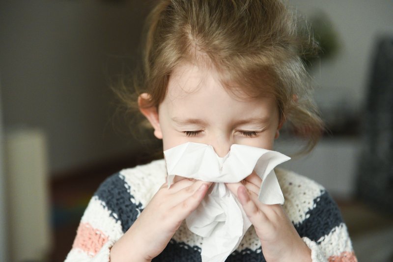 little girl with cold blowing nose