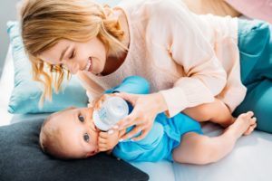 Baby drinking bottle while lying on bed