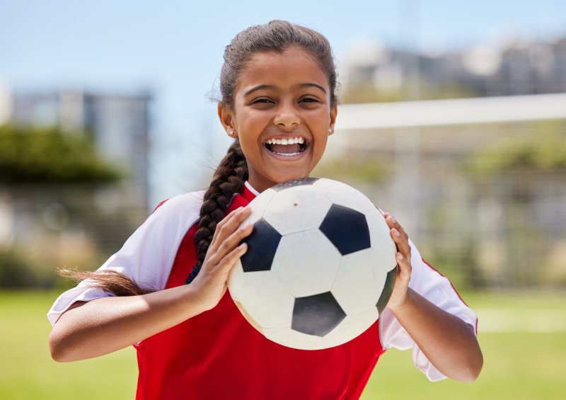 young girl smiling and holding soccer ball 