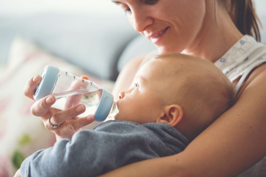 A mother feeding a baby a bottle of water