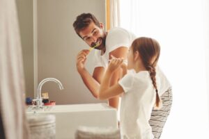 Dad and daughter brushing their teeth together