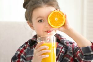 Young girl drinking orange juice.